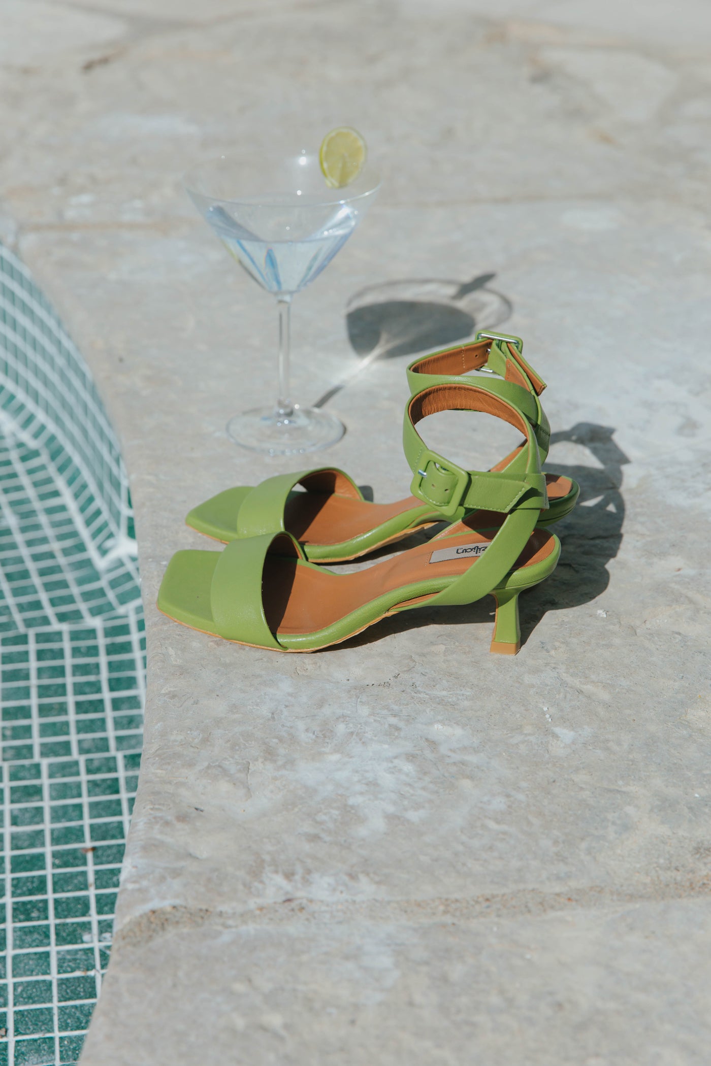 Sandálias de senhora kitten heel em pele com tiras cruzadas no tornozelo e fivela ajustável. Disponíveis em prerto, toupeira, verde e rosa