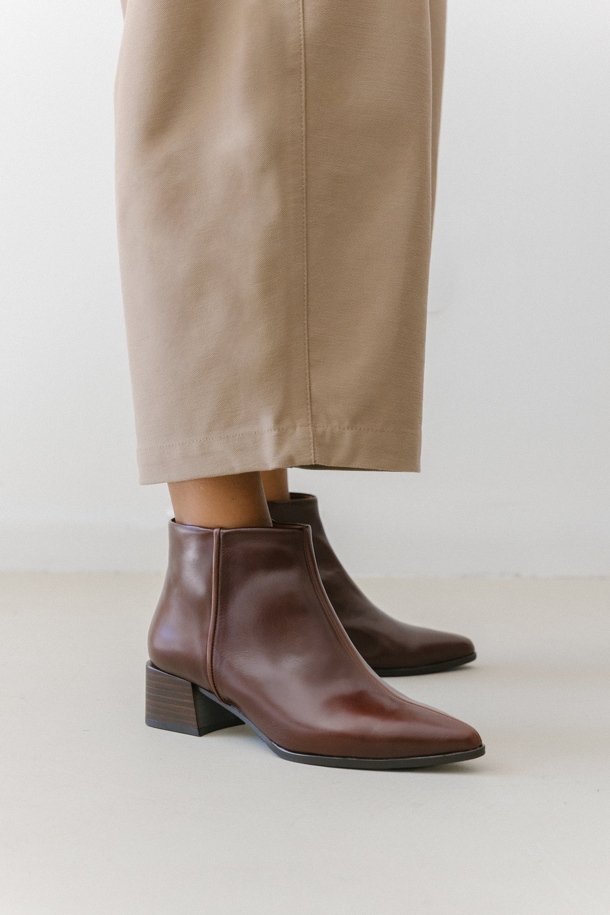 Botins bordeaux em pele usados com calças largas em bege.