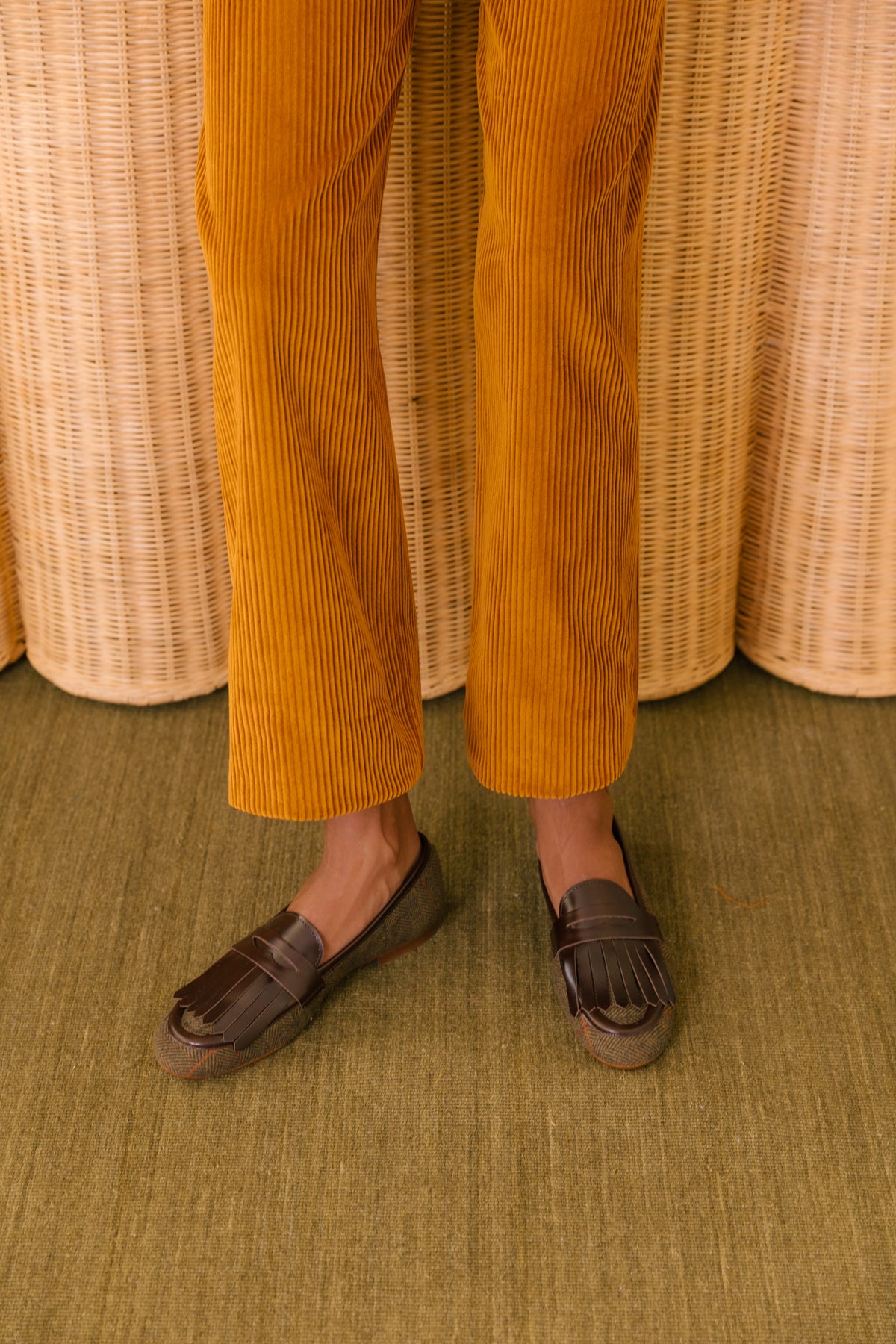 Loafers rasos em tweed com franjas em pele castanha, usados com calças de bombazina mostarda