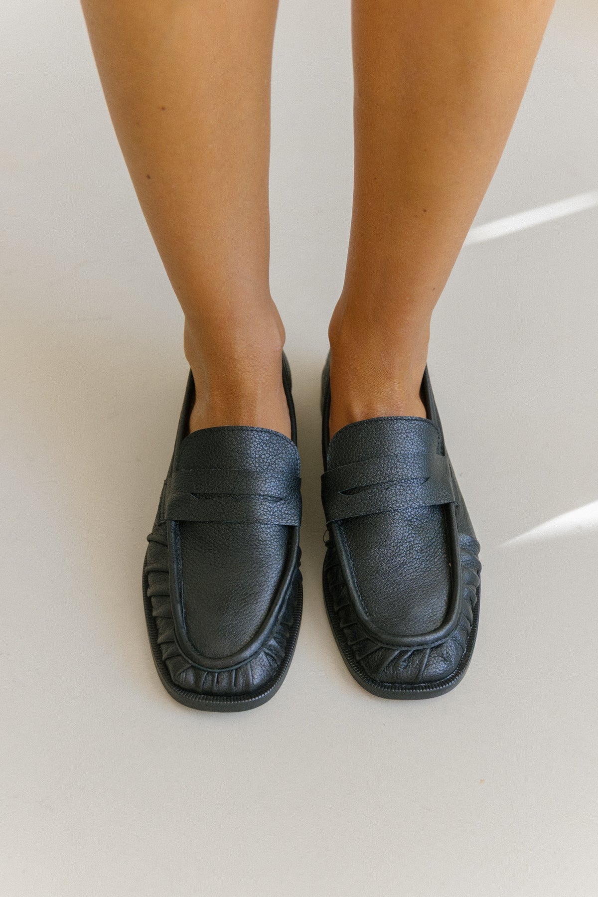 Par de loafers pretos vistos de cima, com o franzido à volta da biqueira.