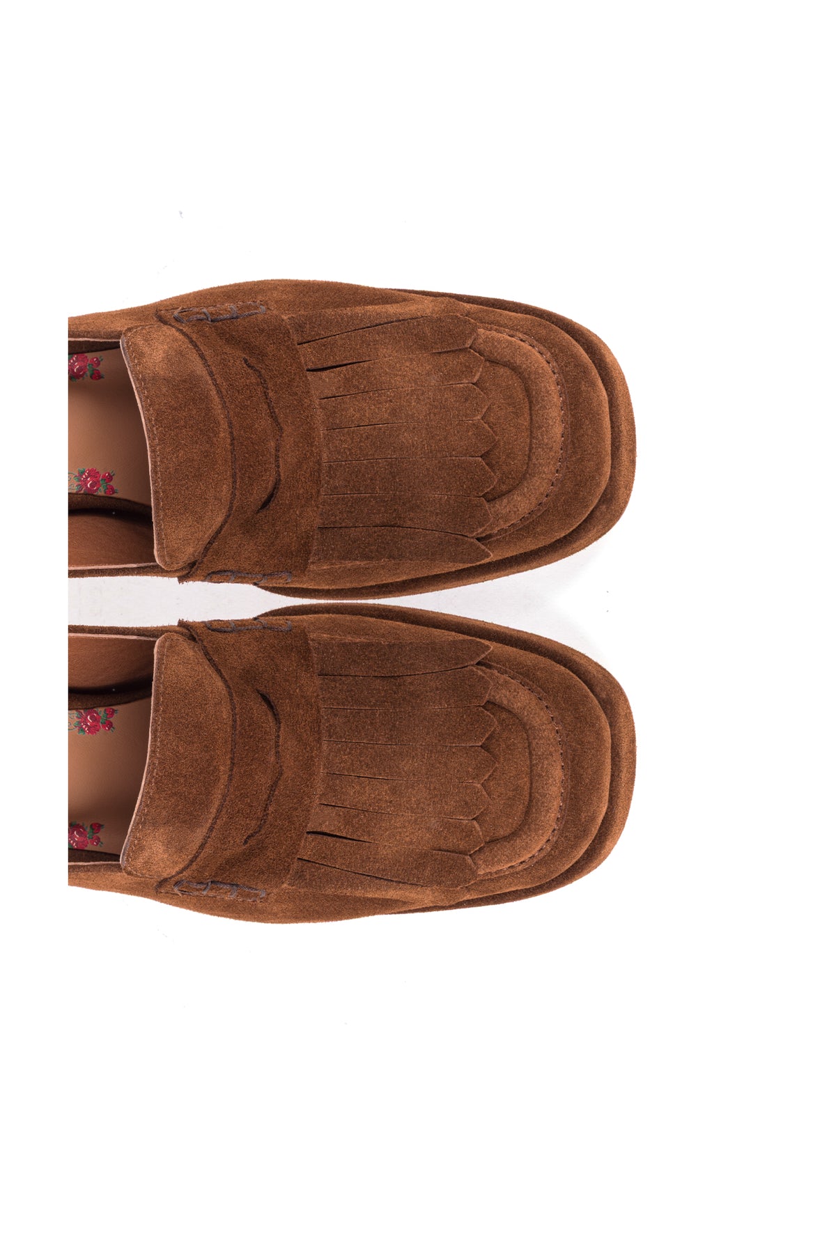 Par de loafers slingback em croute castanho visto de cima, com as franjas e a palmilha estampada a flores.