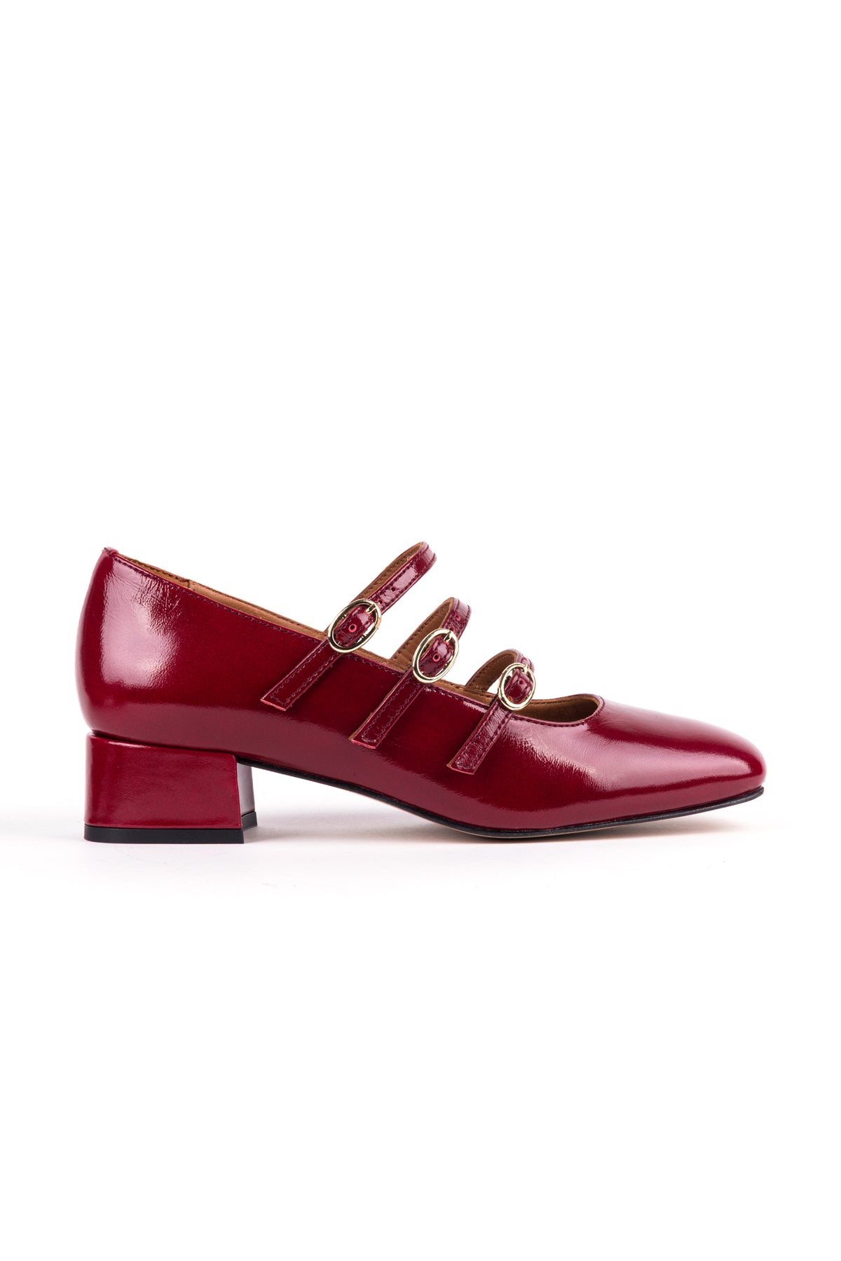 Mary Janes em pele envernizada bordeaux, com três tiras e fivelas douradas.